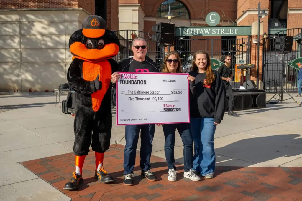 A corporate partner presenting a donation cheque to The Baltimore Station